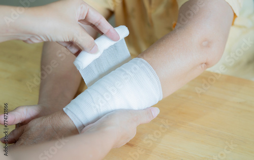 Daughter wraps bandage around mom's wrist in the event of a sprain or accident at home. photo