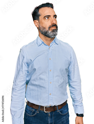 Middle aged man with beard wearing business shirt smiling looking to the side and staring away thinking.