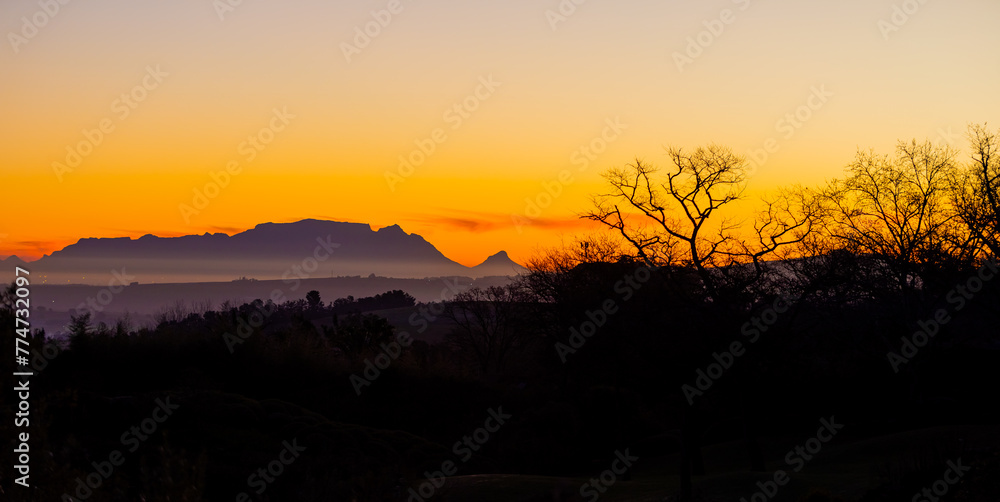 Fototapeta premium Silhouette of Table Mountain against a dusk sunset sky in Cape Town