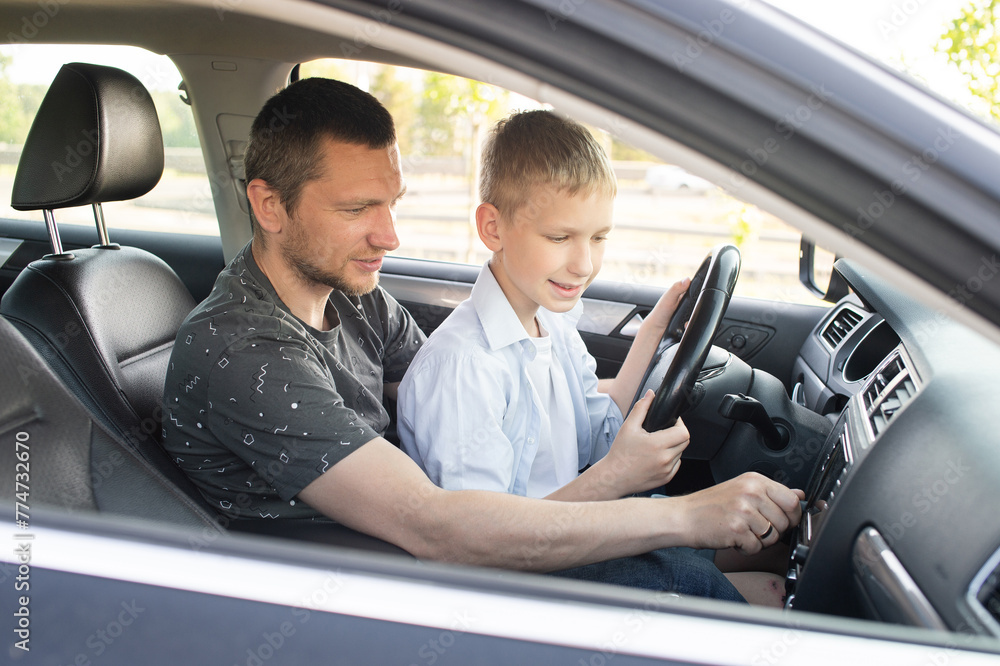 Obraz premium Dad shows his son how to drive a car. The child is driving with dad. Global Day of Parents