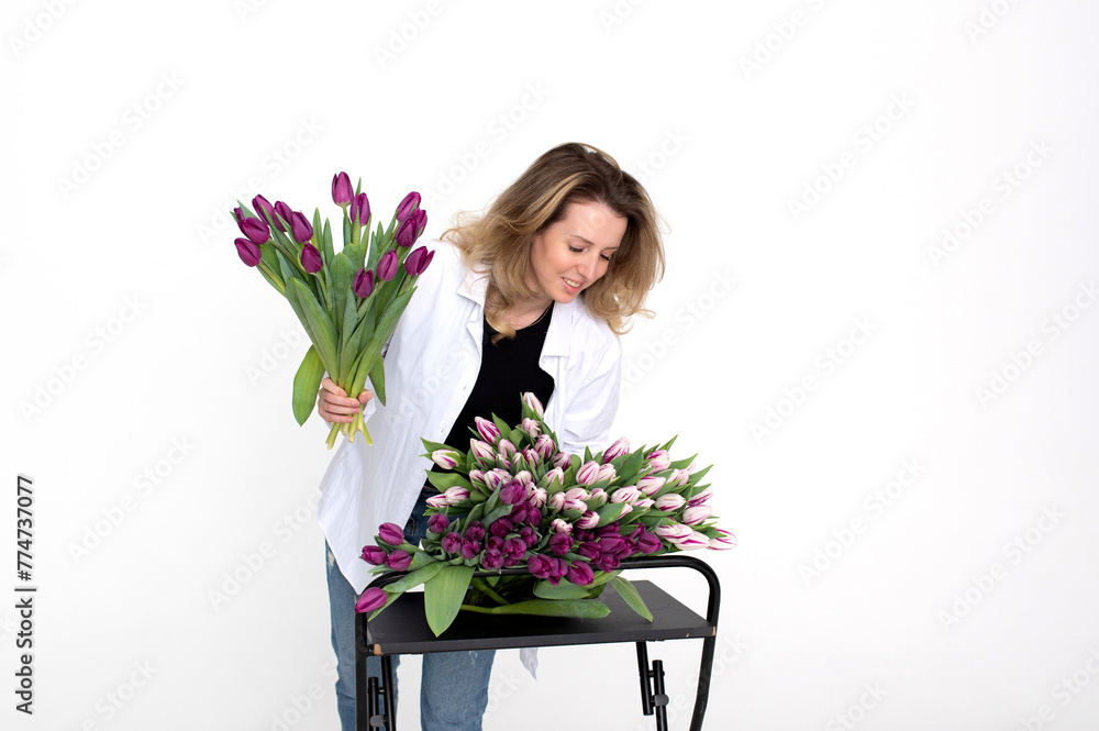 A lovely girl leaned over a table with different varieties of tulips. Bouquet of purple tulips A lovely girl leaned over a table with different varieties of tulips. Bouquet of purple tulips