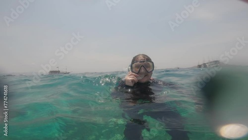 POV footage from a GoPro captures a woman floating on the surface of the sea, wearing a diving mask. Perfect for adventure, travel, and water sports enthusiasts.