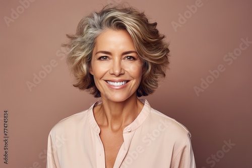 A woman with a short, gray hair is smiling and wearing a pink shirt