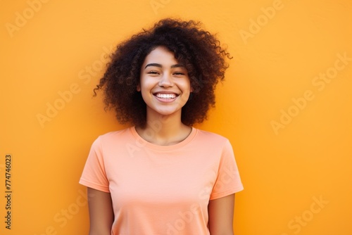 A woman with curly hair is smiling and wearing an orange shirt © Juan Hernandez
