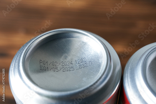 Close-up of expiration date of aluminum cans on wooden table, shallow depth of field.
