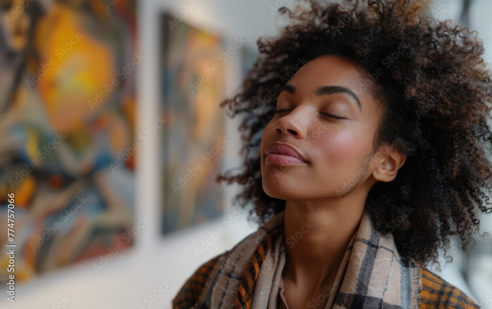 A woman with a plaid scarf is sitting in front of a painting. She is looking at the painting and she is in a relaxed state A woman with a plaid scarf is sitting in front of a painting. She is looking at the painting and she is in a relaxed state