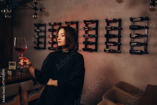 Картината върху платно Woman in the wine cellar with barrels in background drinking and tasting wine