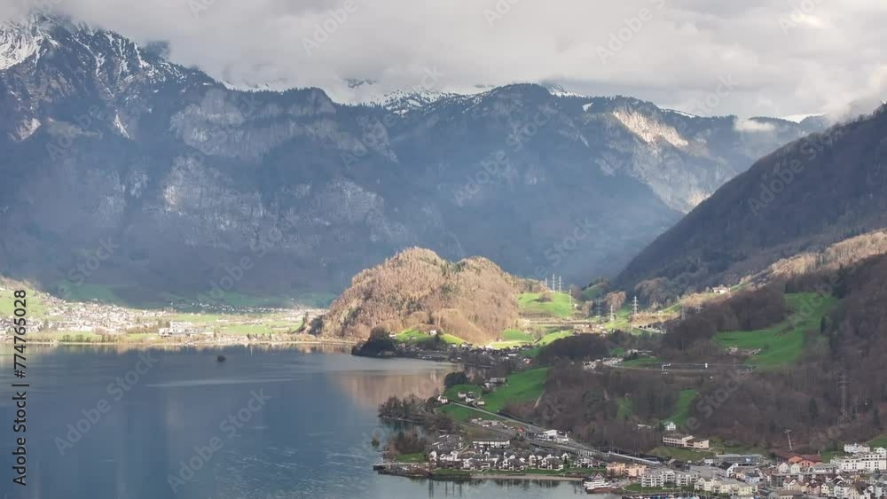 Drone shot over the Walensee in Unterterzen Mols in Switzerland - lakeshore with houses and high mountains in the background