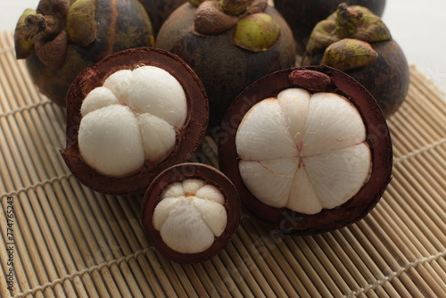 Cut open mangosteen on bamboo base. Mangosteen is popular as Queen of fruit that that has many uses, one of them is traditional medicine. 