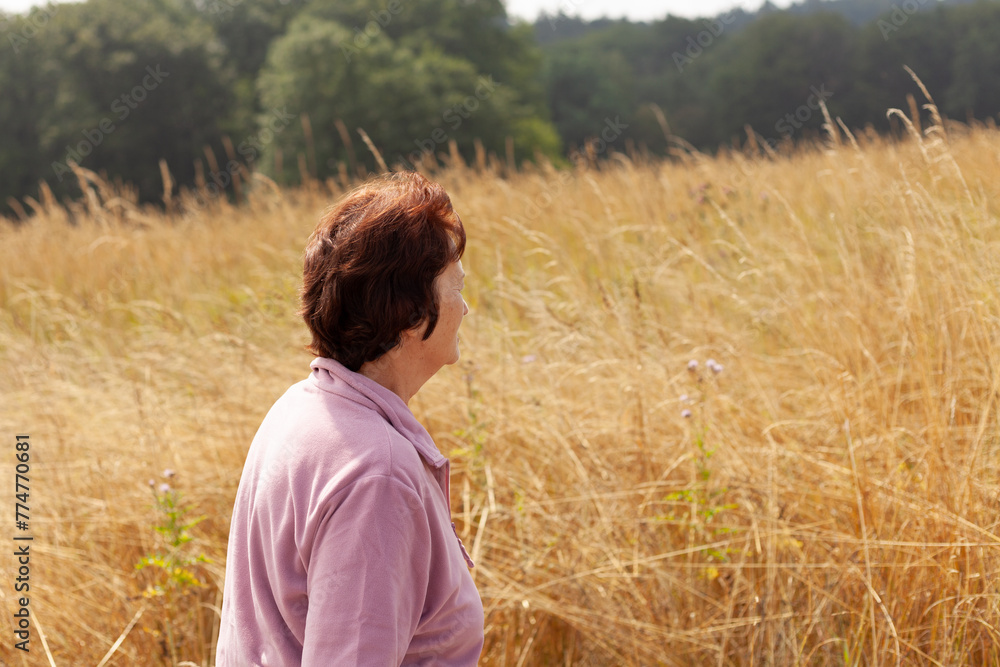Mature woman standing in the middle of a field of tall grass Mature woman standing in the middle of a field of tall grass
