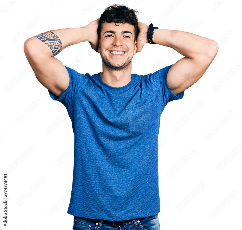 Young hispanic man wearing casual t shirt relaxing and stretching, arms and hands behind head and neck smiling happy Young hispanic man wearing casual t shirt relaxing and stretching, arms and hands behind head and neck smiling happy