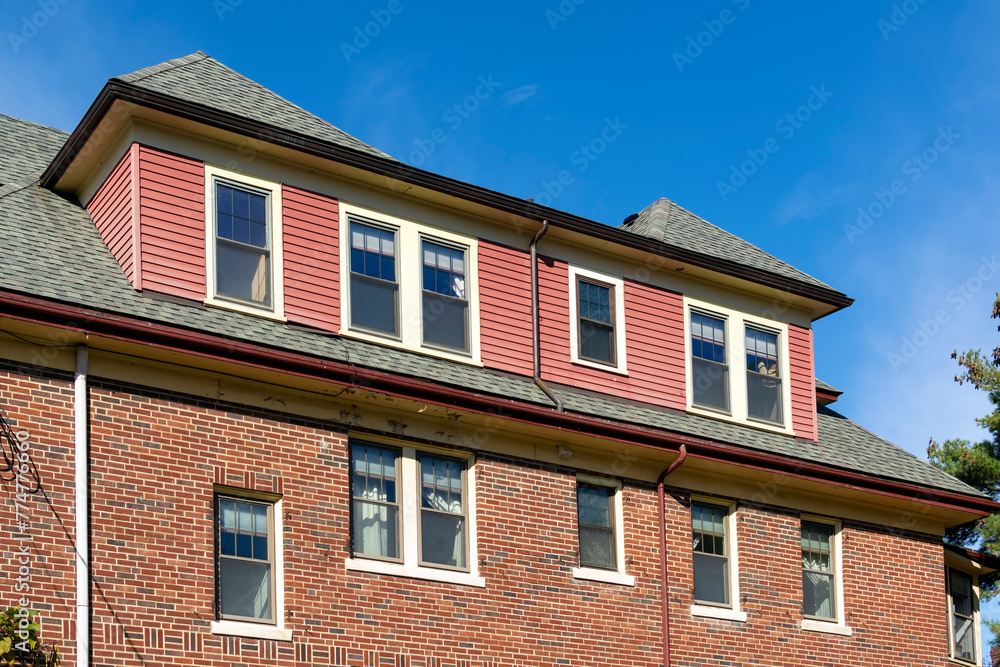 Red brick building with dormer windows protrudes from the roof in Brighton, Massachusetts, USA