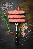 Slices of beef steak on a metal fork on a dark background. Top view. Free space for text.
