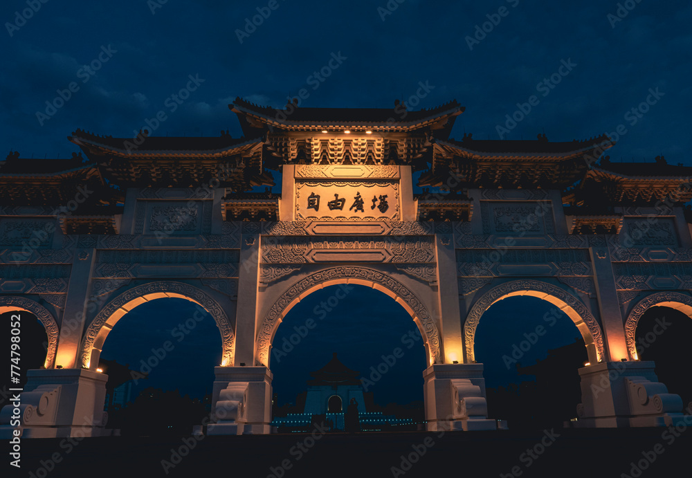 Obraz premium Main gate at Chiang Kai-shek Mausoleum Memorial Monument at night in Freedom Square, Taipei, Taiwan. Panoramic view of Memorial Hall Square. National monument. Dark sky with clouds in a dark blue sky