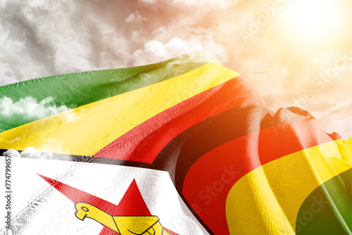 Zimbabwe national flag cloth fabric waving on beautiful cloudy Background. photo