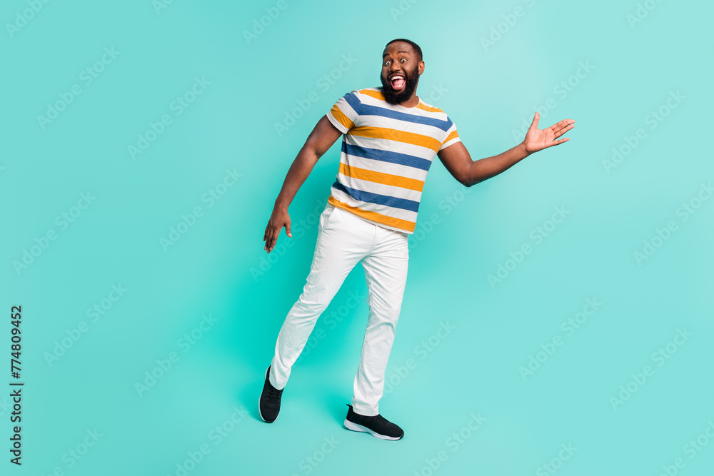 Full length photo of carefree cool man wear striped t-shirt having fun isolated teal color background