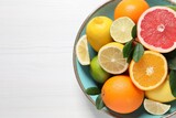 Different cut and whole citrus fruits on white wooden table, top view. Space for text