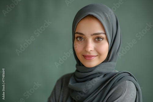 Portrait of young smiling Arabian muslim woman in abaya on green background with copy space
