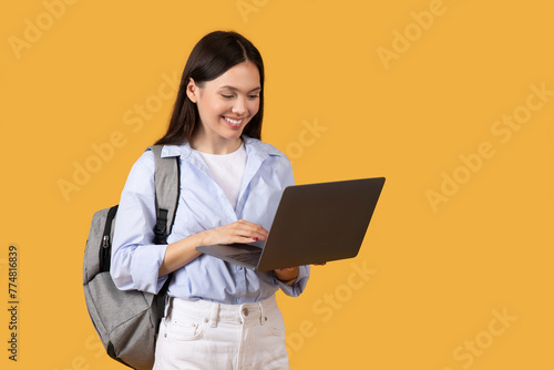 Happy Student with Laptop and Backpack against yellow background