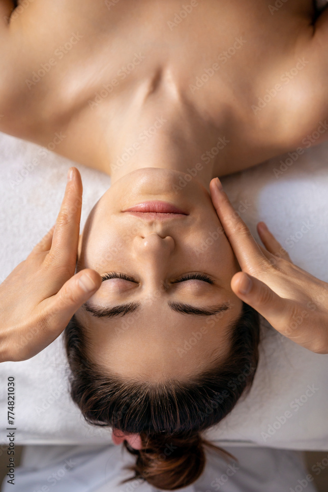 Obraz premium Top view of young woman getting spa massage treatment at beauty spa salon. Facial beauty treatment. Face massage. Spa skin and body care.