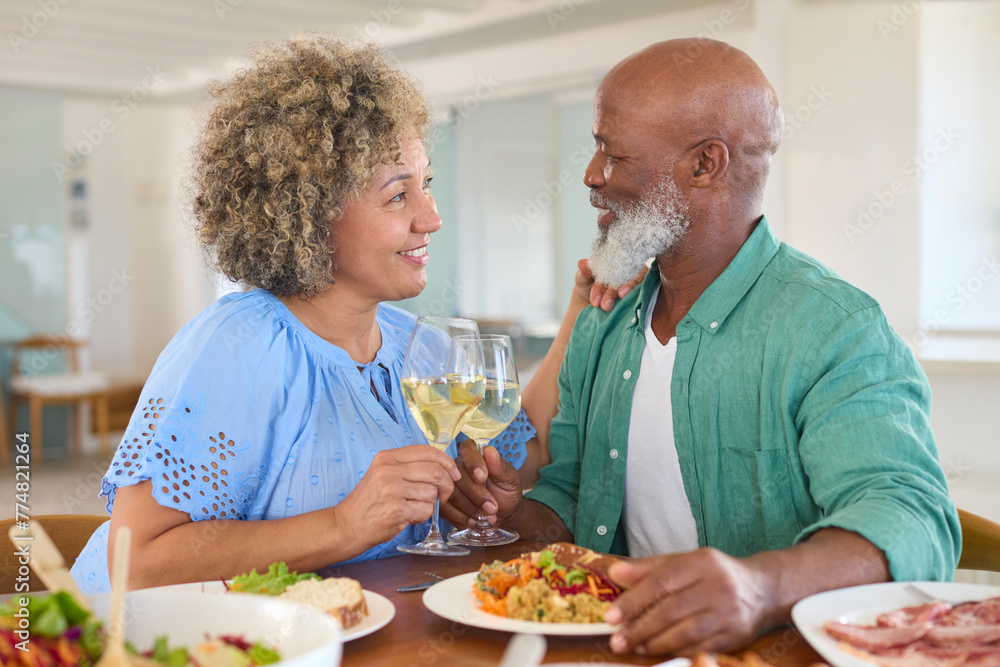 Loving Mature Couple At Home Enjoying Lunch With Wine Together
