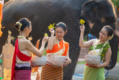 Songkran festival. Northern Thai people in Traditional clothes dressing splashing water together in Songkran day cultural festival with elephant background. © Quality Stock Arts