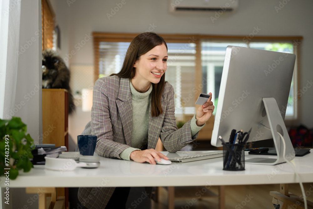 Happy young woman holding plastic credit card and typing on keyboard. Online shopping concept Happy young woman holding plastic credit card and typing on keyboard. Online shopping concept
