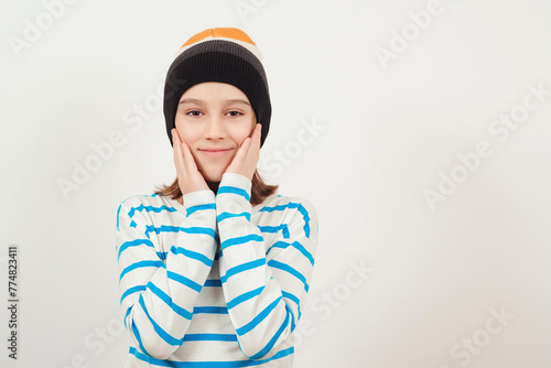 Stylish confident boy smiling over white background. Cute guy wearing woolen hat. Portrait of eleven years old boy.