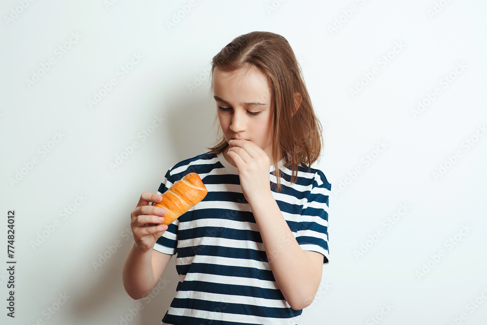 Happy boy holding tasty bun with sausage. Hungry boy eating snack.