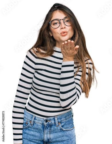 Young beautiful teen girl wearing casual clothes and glasses looking at the camera blowing a kiss with hand on air being lovely and sexy. love expression.