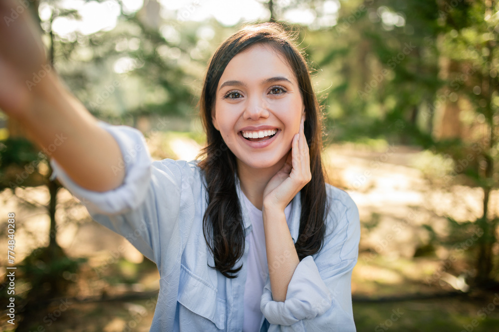 Smiling woman taking selfie in sunlit park Smiling woman taking selfie in sunlit park