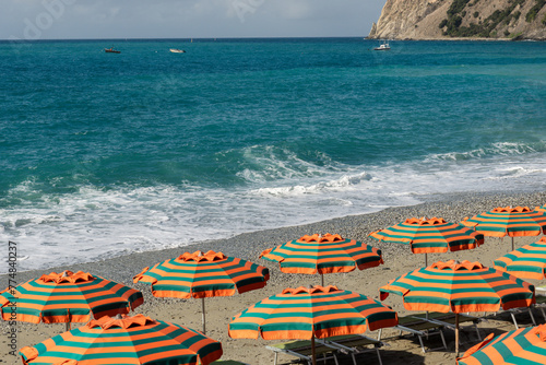 Striped colorful umbrellas and sun beds at Monterosso al Mare beach in the morning