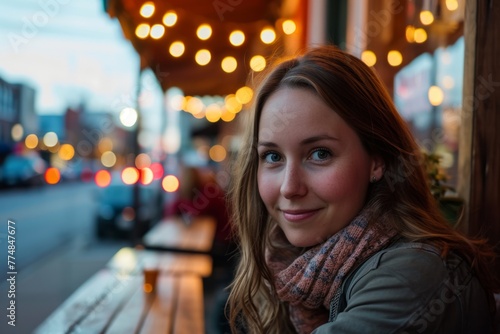 Portrait of a beautiful young woman sitting in a cafe on the street at night