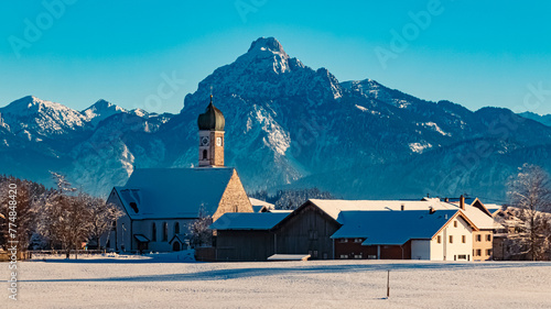 Church on a sunny winter day with the alps in the background near Eisenberg, Ostallgaeu, Bavaria, Germany photo