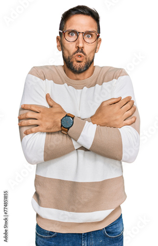 Handsome man with beard wearing casual clothes and glasses shaking and freezing for winter cold with sad and shock expression on face