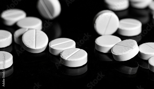 Close up of white painkiller tablet on a reflective black backgr