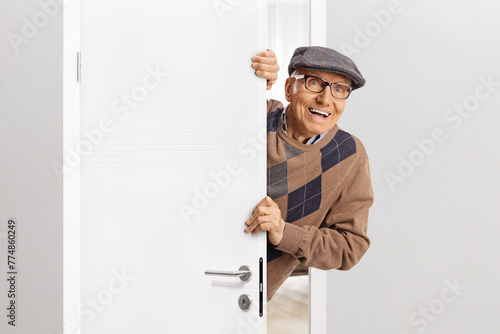 Obraz na plátne Elderly man standing behind a door