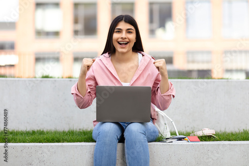 Foto Excited young lady celebrating success with laptop