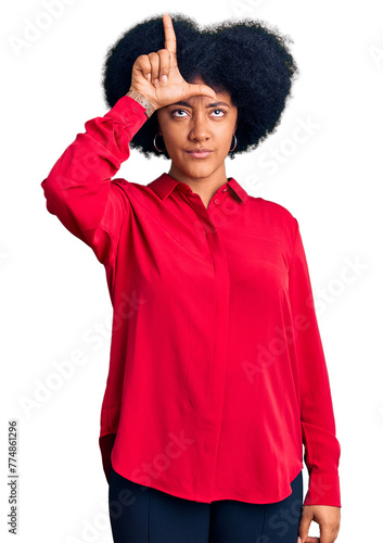 Young african american girl wearing casual clothes making fun of people with fingers on forehead doing loser gesture mocking and insulting.