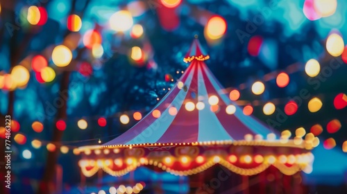 Blurred circus tent with lights garland in night park. Concept of carnival and holidays.