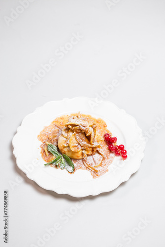 Top view of a delicious pancake with berries and mint leaves on a white plate