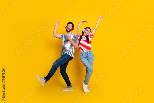 Full length photo of nice positive people listen favorite song dancing rejoice isolated on yellow color background