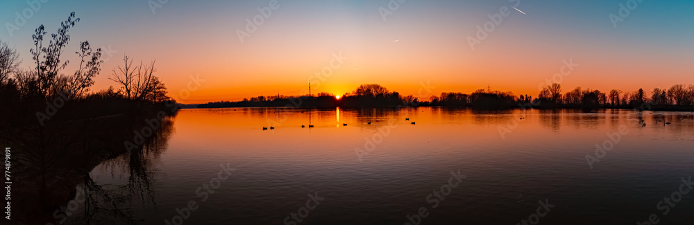 High resolution stitched winter sunset panorama with reflections and swans near Plattling, Isar, Bavaria, Germany