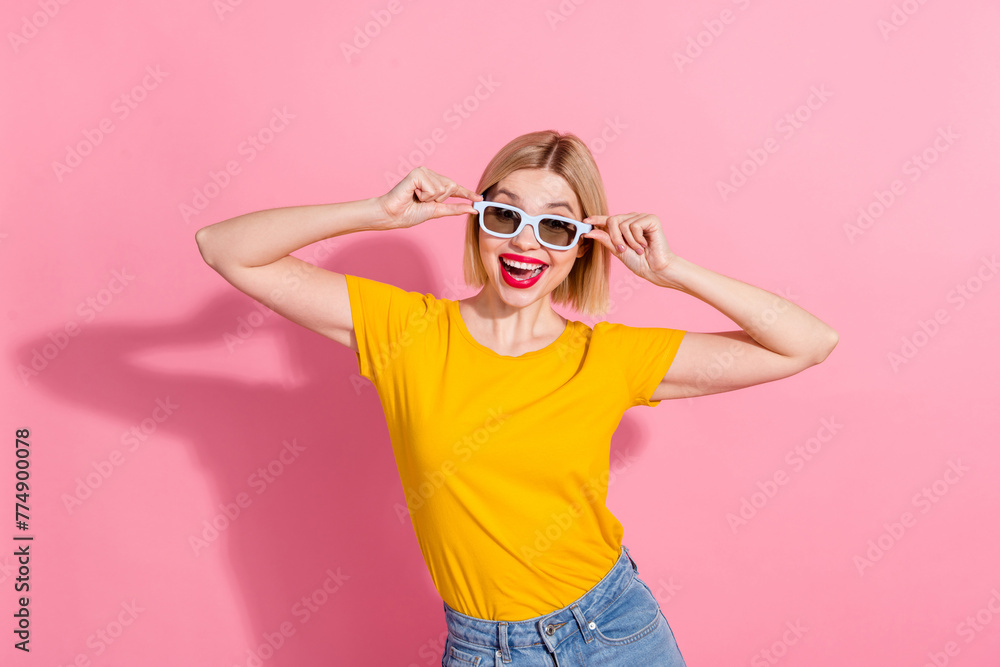 Photo of cheerful carefree lady dressed yellow t-shirt hands arms dark eyewear smiling isolated pink color background Photo of cheerful carefree lady dressed yellow t-shirt hands arms dark eyewear smiling isolated pink color background