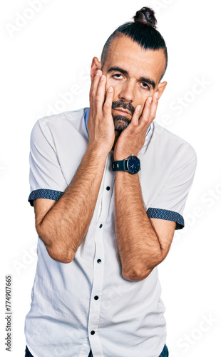 Hispanic man with ponytail wearing casual white shirt tired hands covering face, depression and sadness, upset and irritated for problem © Krakenimages.com