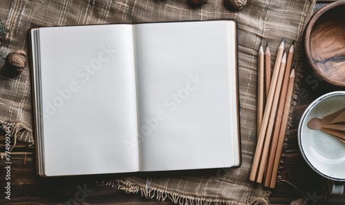 A sketchbook open to a blank page with graphite pencils beside it