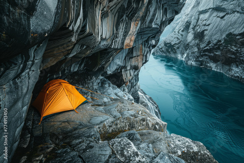 orange tent is pitched in a pocket of rocks above the river. photo
