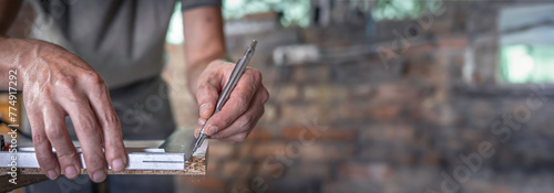 Carpenter holding ruler and pencil while making marks on the wood. photo