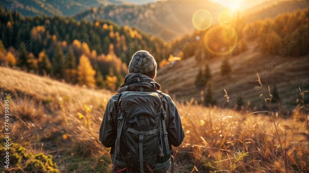 Hiker with backpack on the top of the mountain in the rays of the setting sun Hiker with backpack on the top of the mountain in the rays of the setting sun