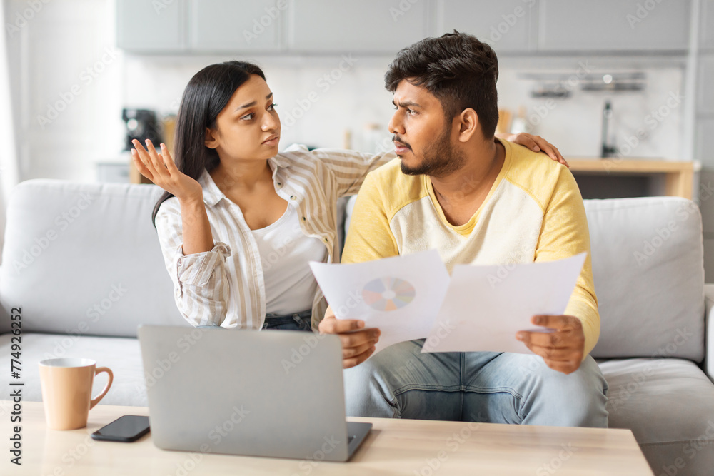 Indian Man and Woman Sitting on Couch Examining Document Indian Man and Woman Sitting on Couch Examining Document